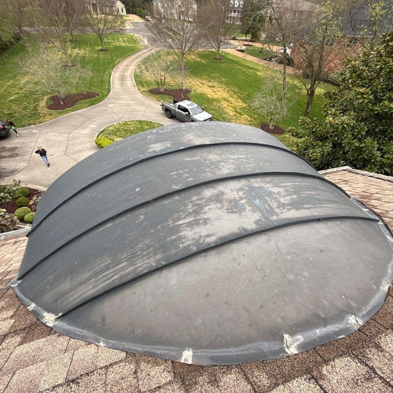 Oval skylight with worn seals on asphalt roof
