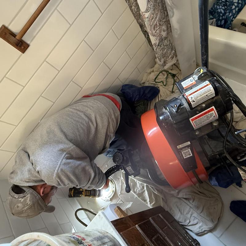 Toilet unclogging with plumbing drain auger in bathroom