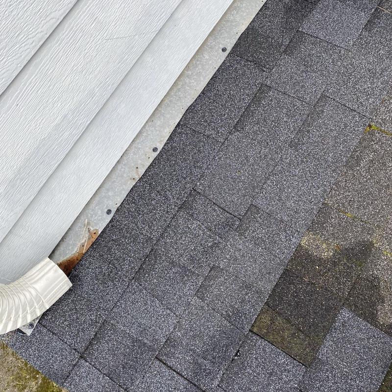Asphalt roof shingles near metal flashing and downspout edge