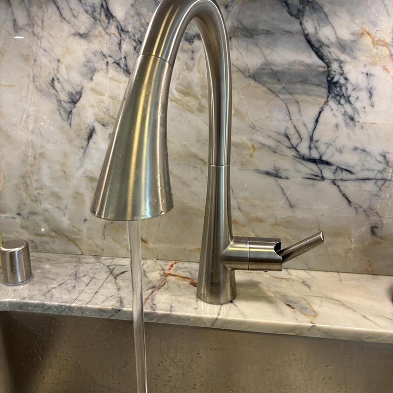 Kitchen faucet with water flowing on marble countertop