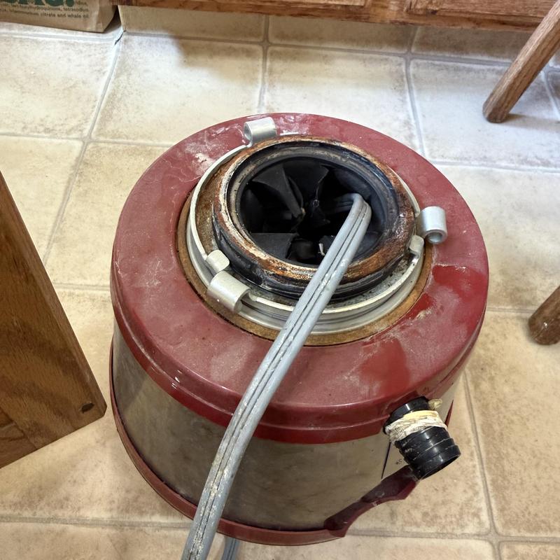 Garbage disposal unit with attached power cord on floor