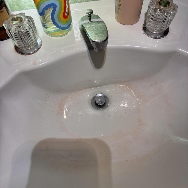 Basin drain with faucet and knobs on countertop
