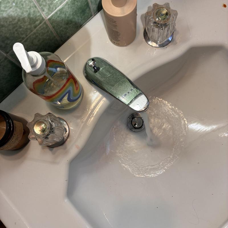 Basin drain clearing with flowing water in bathroom sink