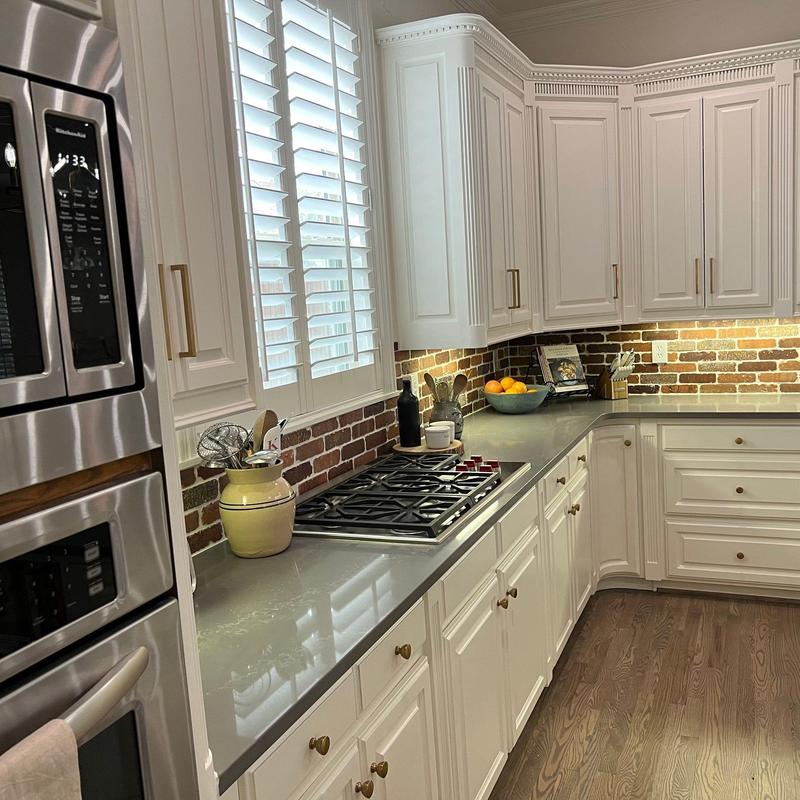 Quartz countertops with brick tile backsplash and white cabinets