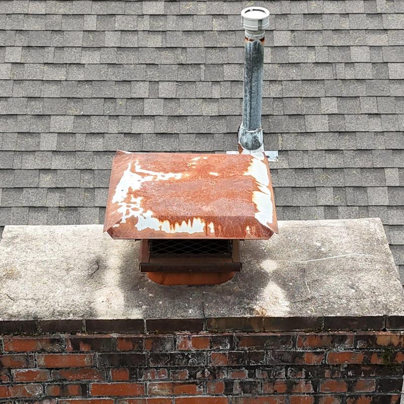 Rusty chimney cap and galvanized vent pipe on shingle roof
