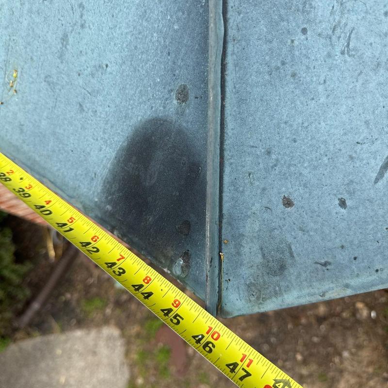Metal roof flashing with measuring tape detailing damage