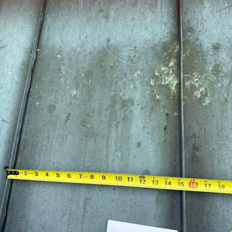 Metal roof panel with measuring tape across section