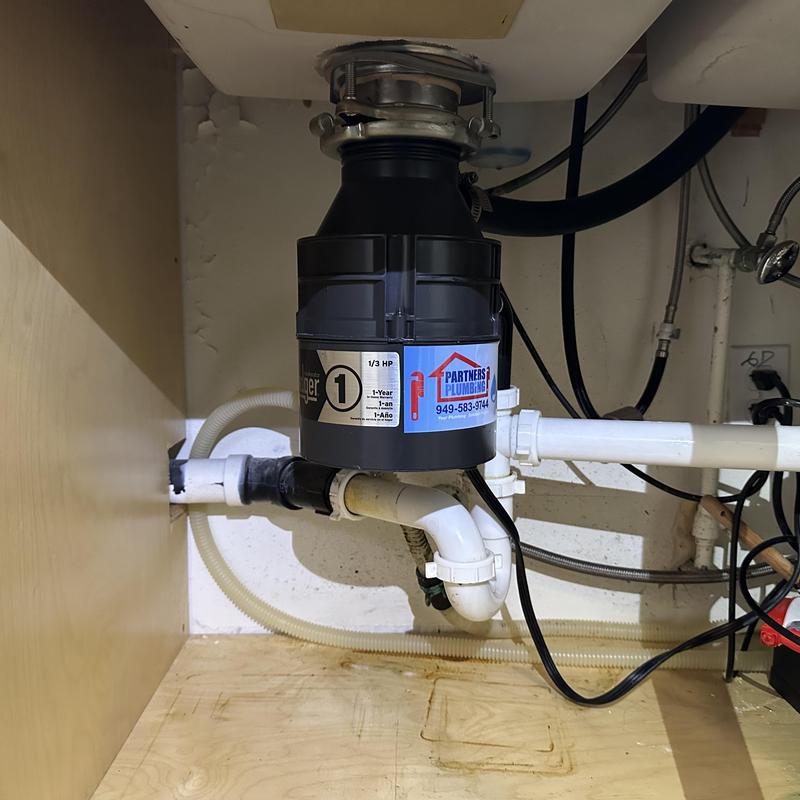 Garbage disposal unit with plumbing connections under sink
