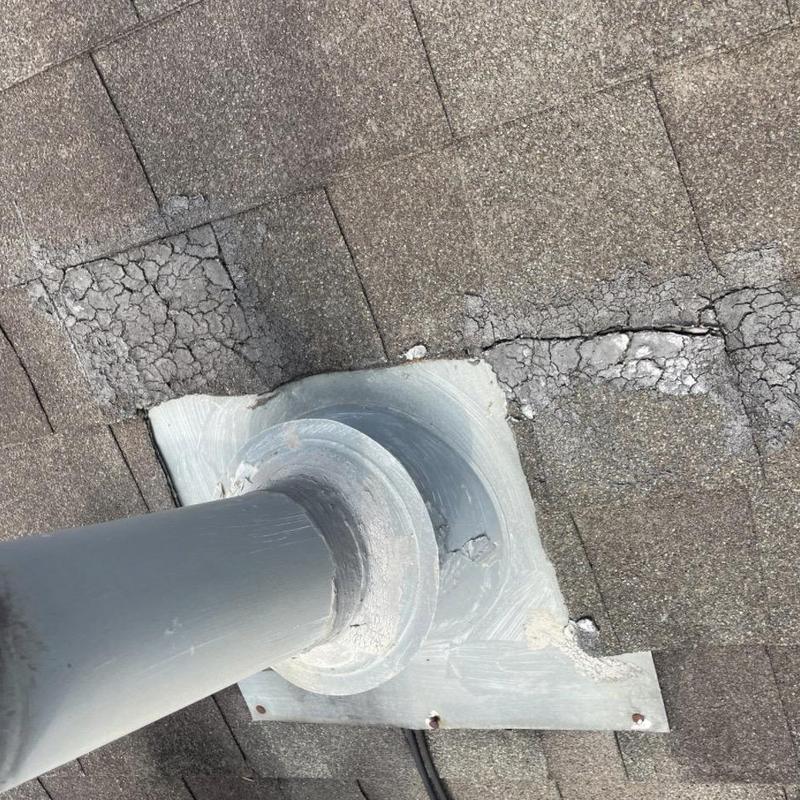 Aged pipe boot flashing with cracked shingles