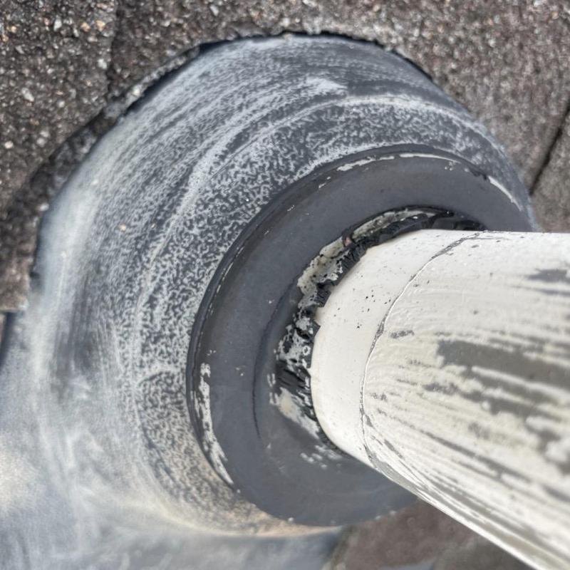 Pipe boot flashing with worn and cracked sealant on roof