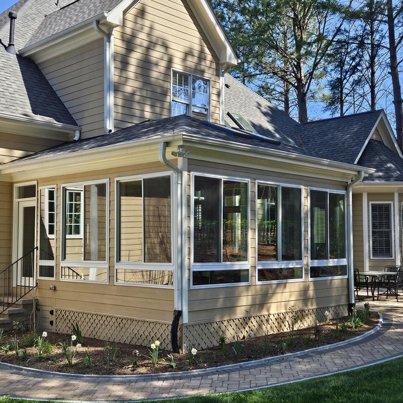 Four-season sunroom with large windows and tan siding Four-season sunroom with large windows and tan siding