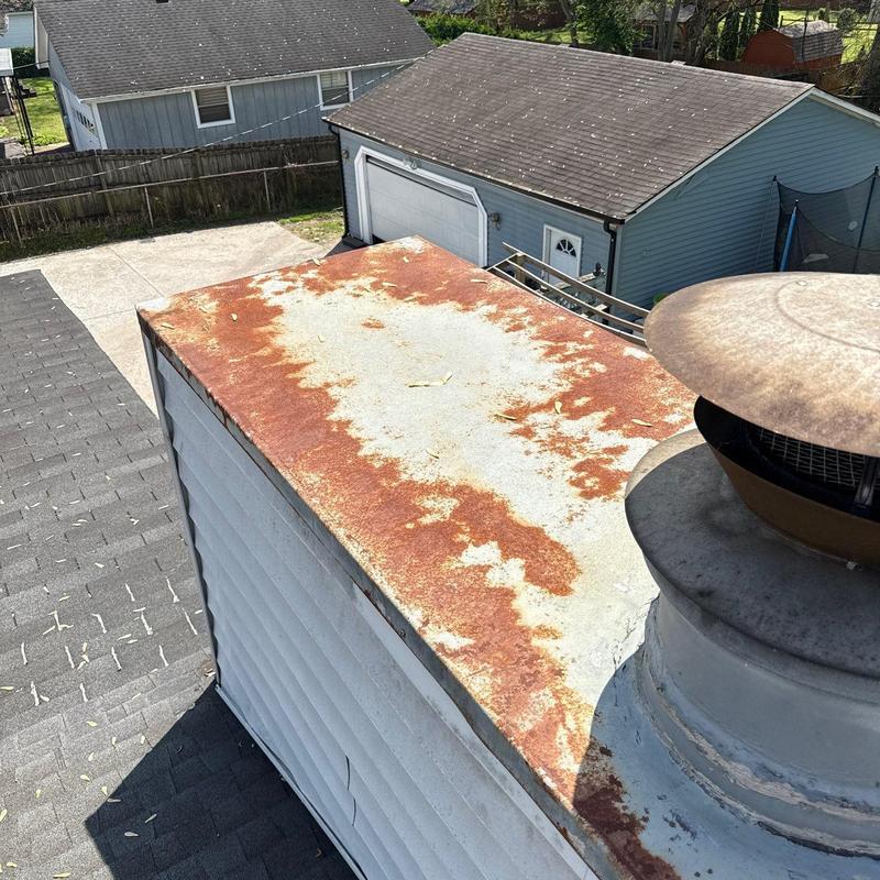 Metal chimney cap corrosion on residential roof