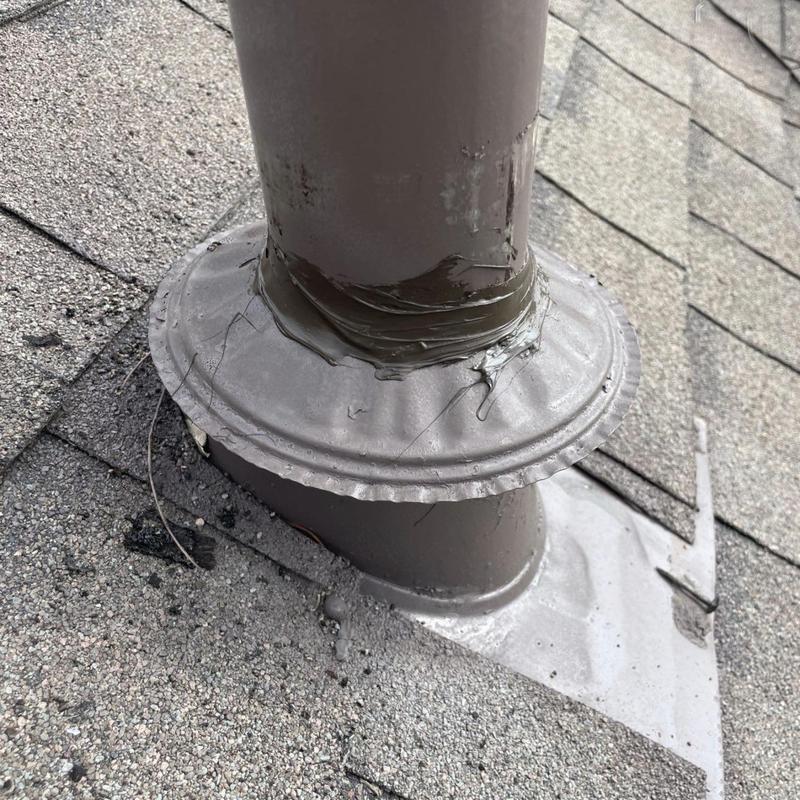 Plumbing vent pipe flashing with sealant on shingle roof