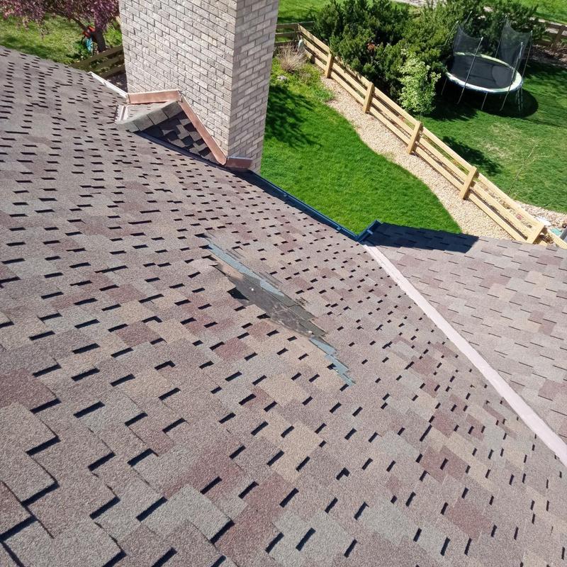 Shingle roof with dislodged shingles near chimney Shingle roof with dislodged shingles near chimney