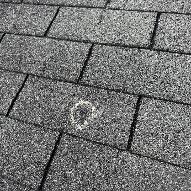 Roof shingle with hail damage marked in chalk Roof shingle with hail damage marked in chalk