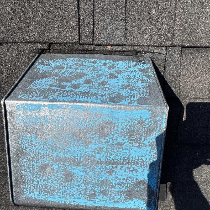 Roof ventilation cap with paint wear on shingles