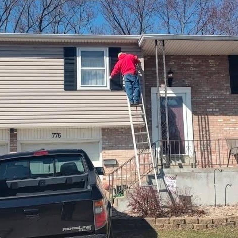 Window shutters repair using ladder on home exterior