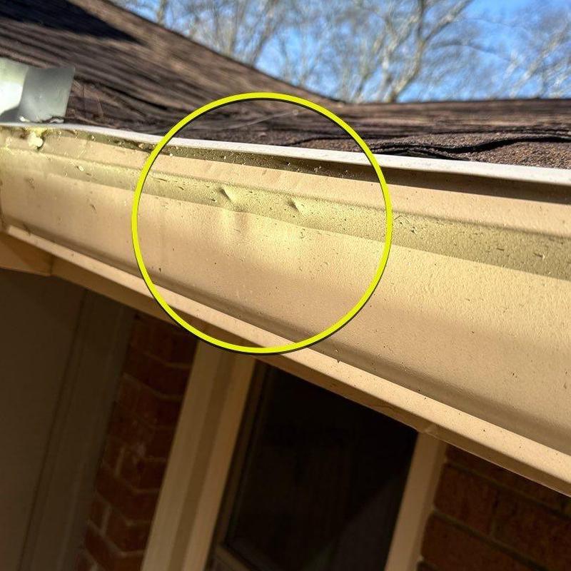 Gutter with hail damage dents on residential roof edge