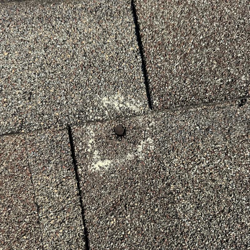 Asphalt shingle roof with improperly installed nail marked Asphalt shingle roof with improperly installed nail marked