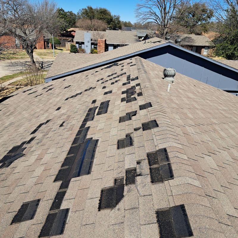 Asphalt shingle roof with wind damage and missing tabs