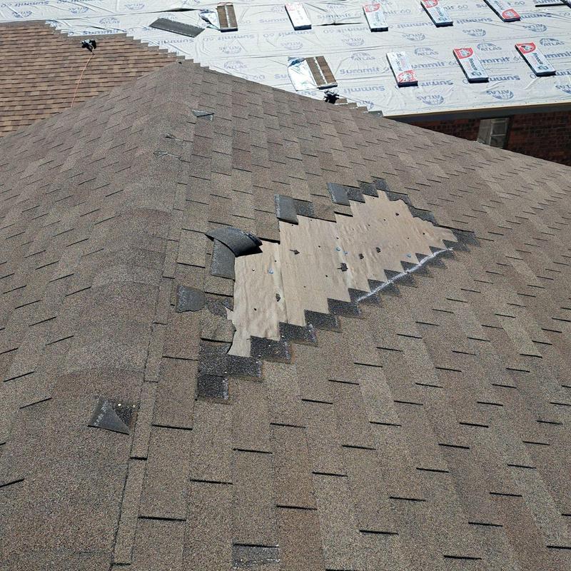 Damaged asphalt roof shingles with exposed roof decking