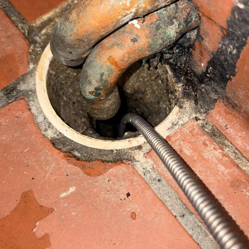Floor drain clearing with cable machine in tile floor