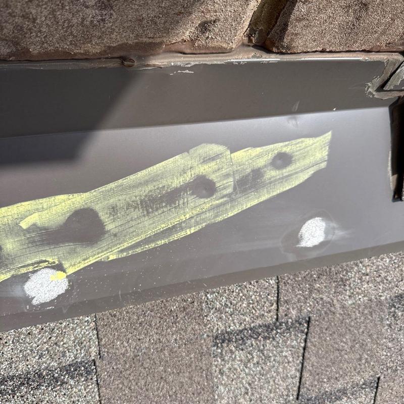 Metal flashing with hail damage markings on roof shingles