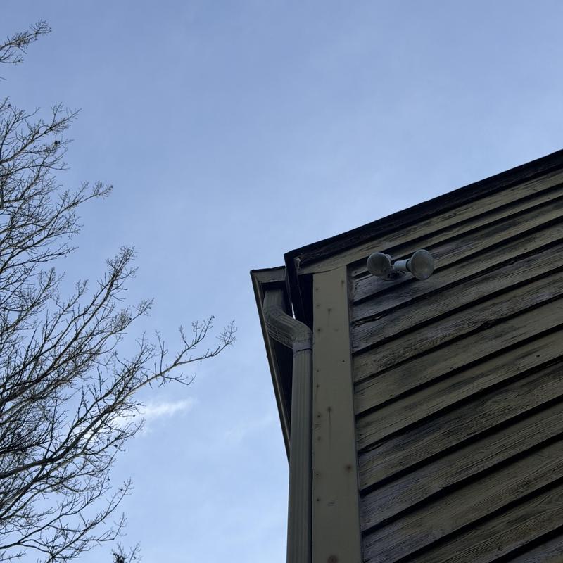 Green 6-inch gutter and two-story downspout on house corner