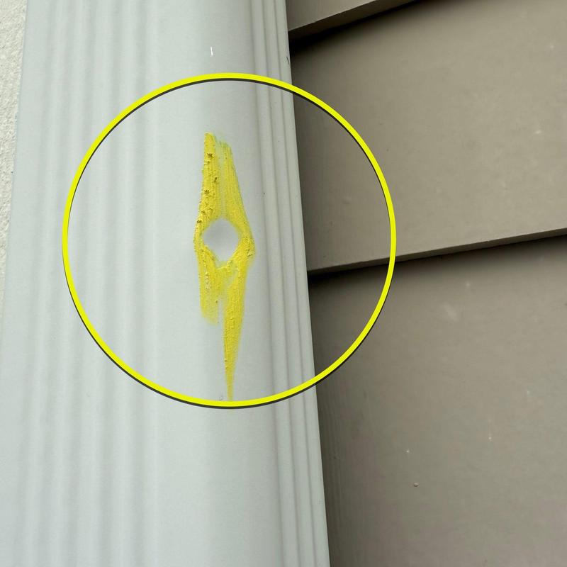 Vinyl siding hole marked for repair in yellow
