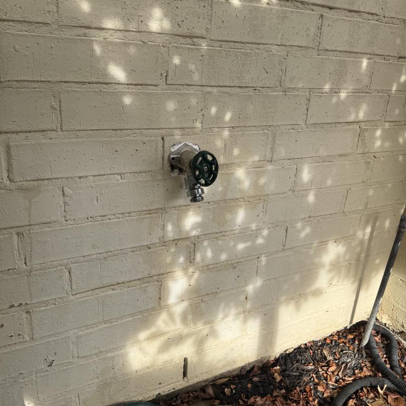 Hose bib valve on exterior brick wall