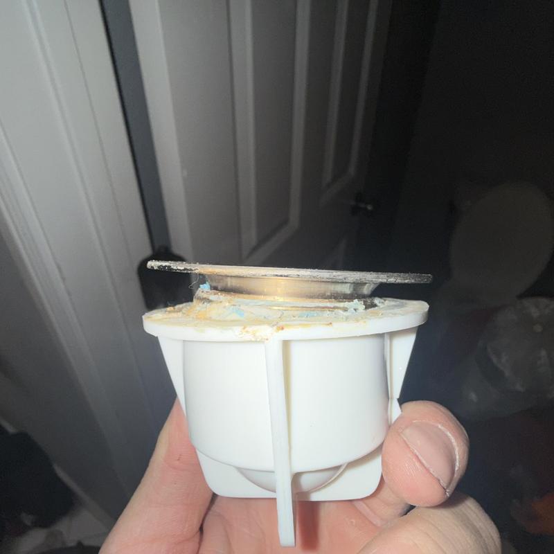 Tub drain strainer with mineral buildup held in hand