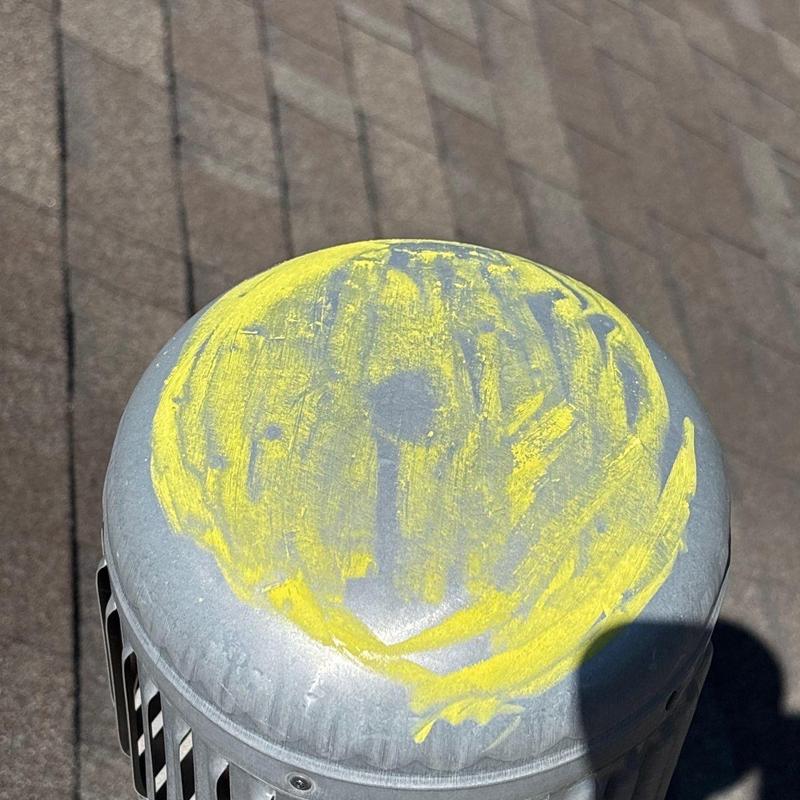 Roof vent cap with yellow chalk markings on shingles