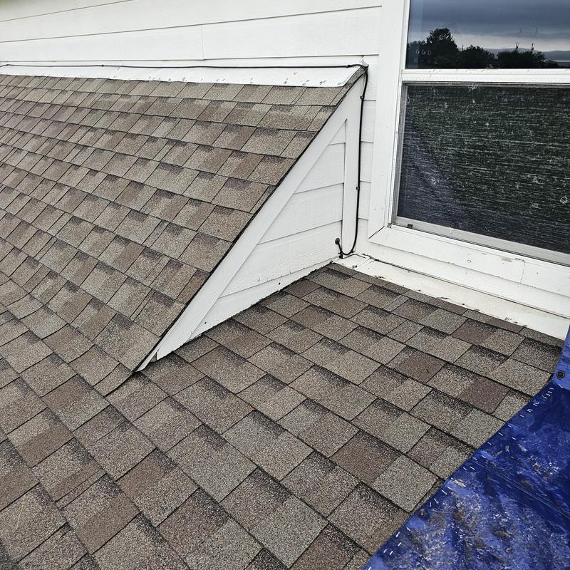 Asphalt shingle roof with hail damage near dormer window