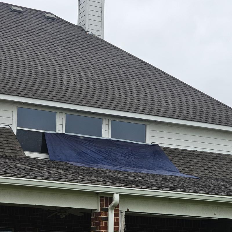 Roof shingles with tarp covering storm damage