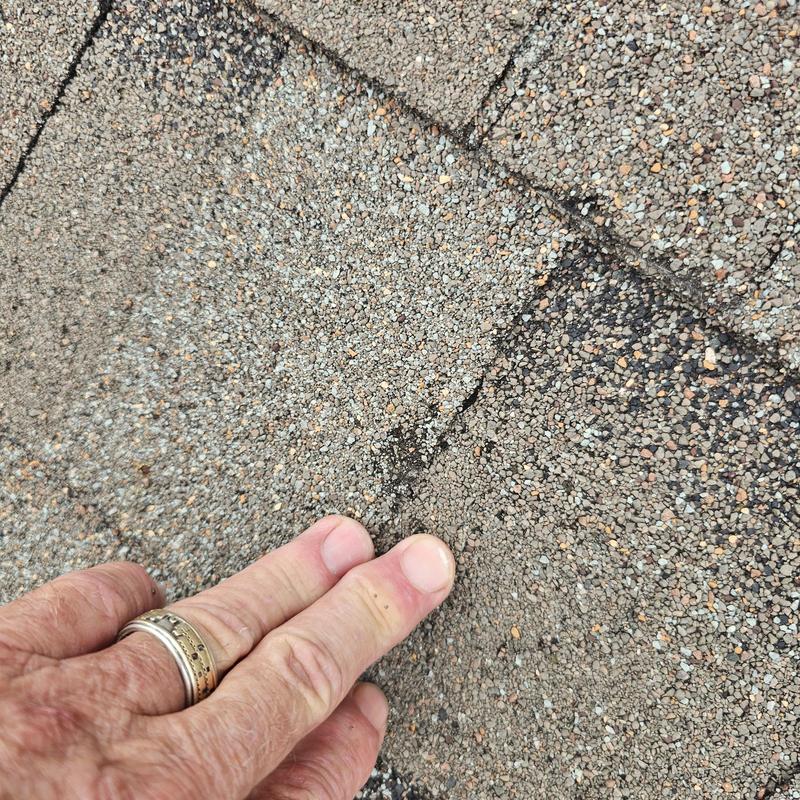 Asphalt roof shingles with wind and hail damage close-up