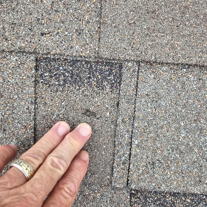 Asphalt roofing shingles with hail impact damage close-up