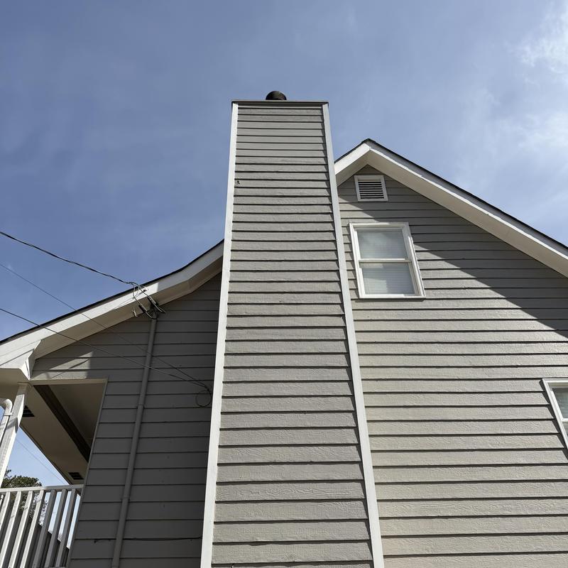 Chimney siding with woodpecker damage on 3-story house