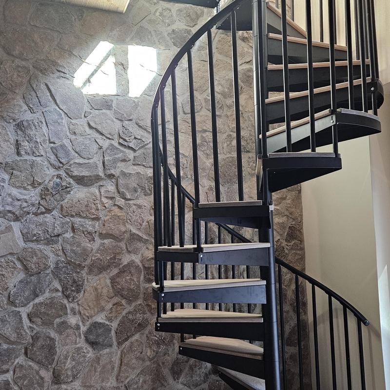 Black metal spiral staircase beside stone wall Black metal spiral staircase beside stone wall