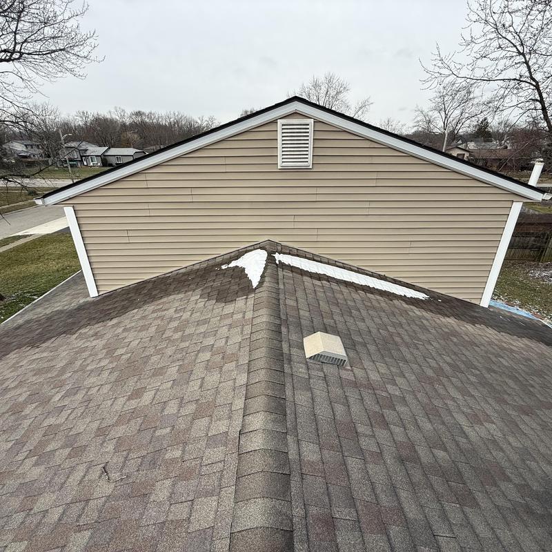 Asphalt shingle roof ridge with vent and snow patches Asphalt shingle roof ridge with vent and snow patches