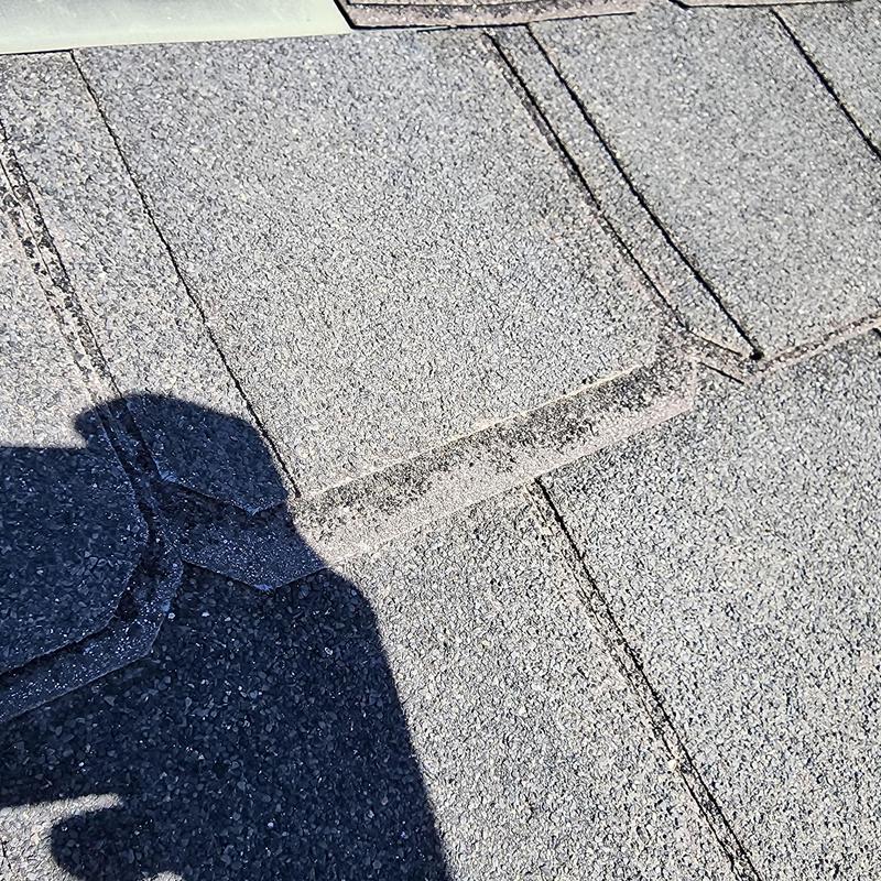 Asphalt roof shingles showing wear and missing metal closures Asphalt roof shingles showing wear and missing metal closures