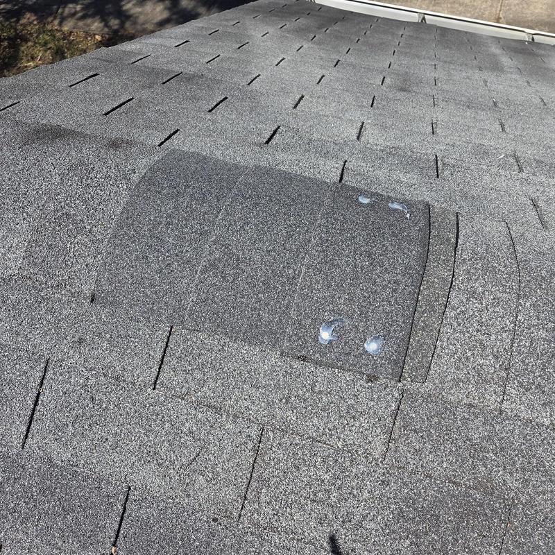 Roof shingles with sealed nail heads on gray roof