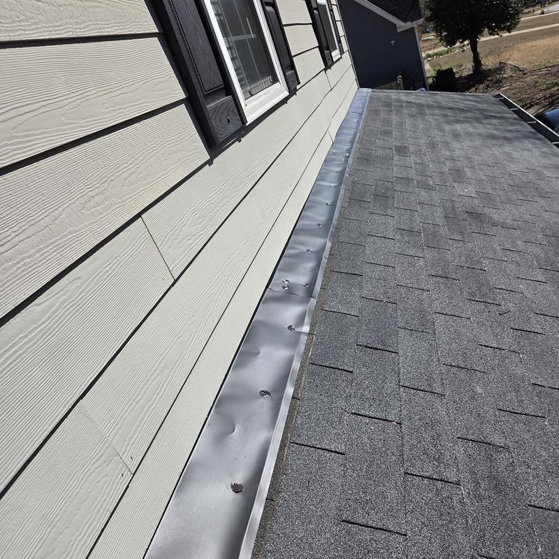 Wall flashing along roof edge with asphalt shingles
