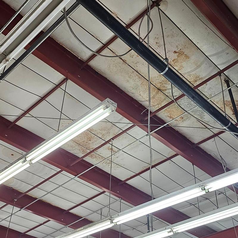 Metal ceiling panels with rust stains and lighting fixtures Metal ceiling panels with rust stains and lighting fixtures