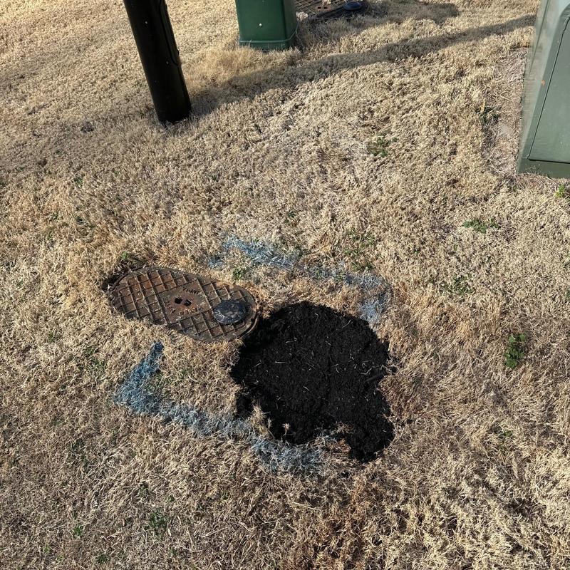 Underground pipe joint excavation with markings on grass Underground pipe joint excavation with markings on grass