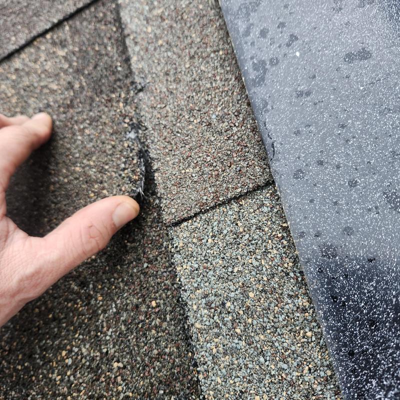 Roof shingle torn near chimney flashing inspection