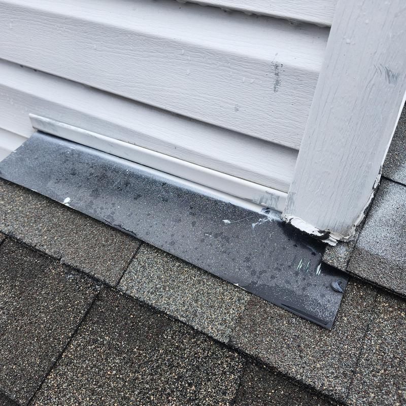 Metal step flashing on roof at wall base