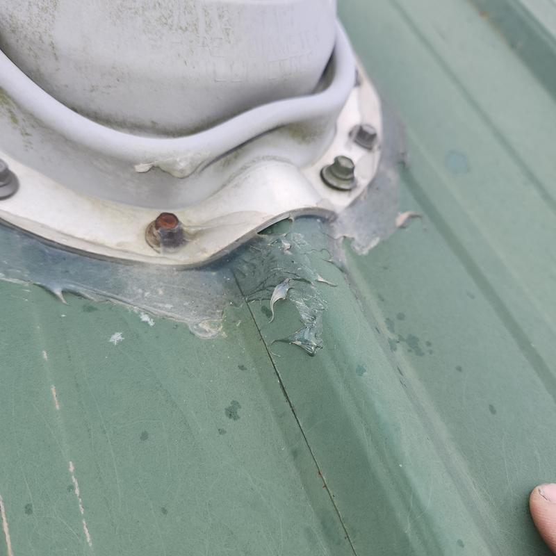 Roof pipe flashing with damaged sealant on metal roof