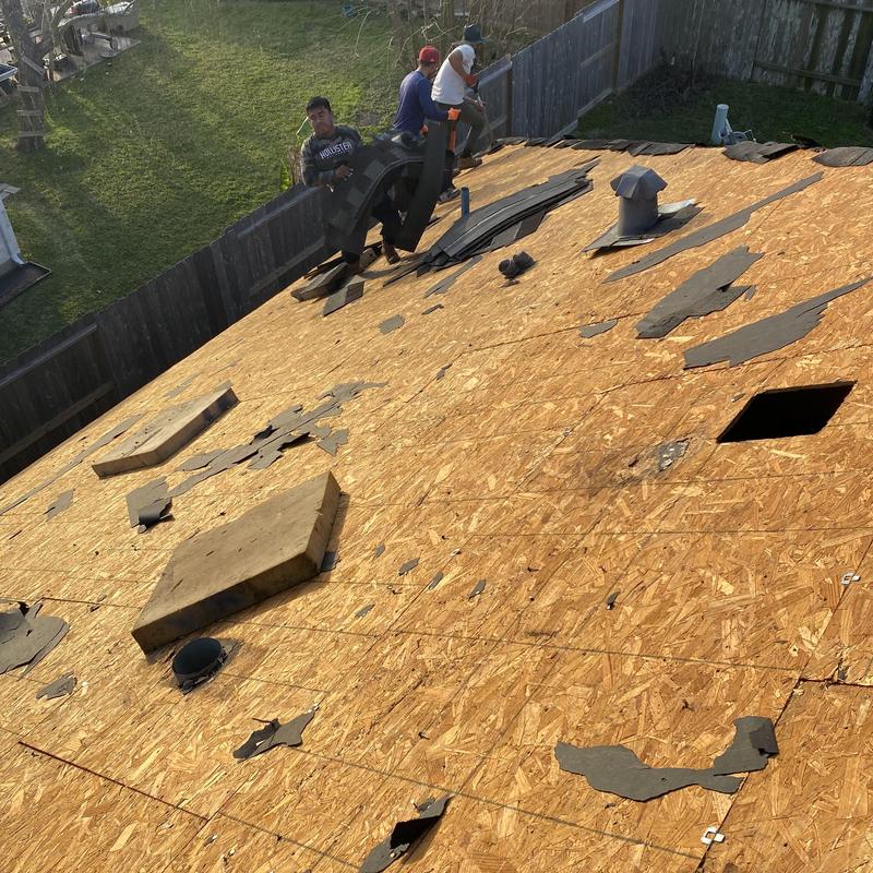 Roof decking removal with workers handling shingles