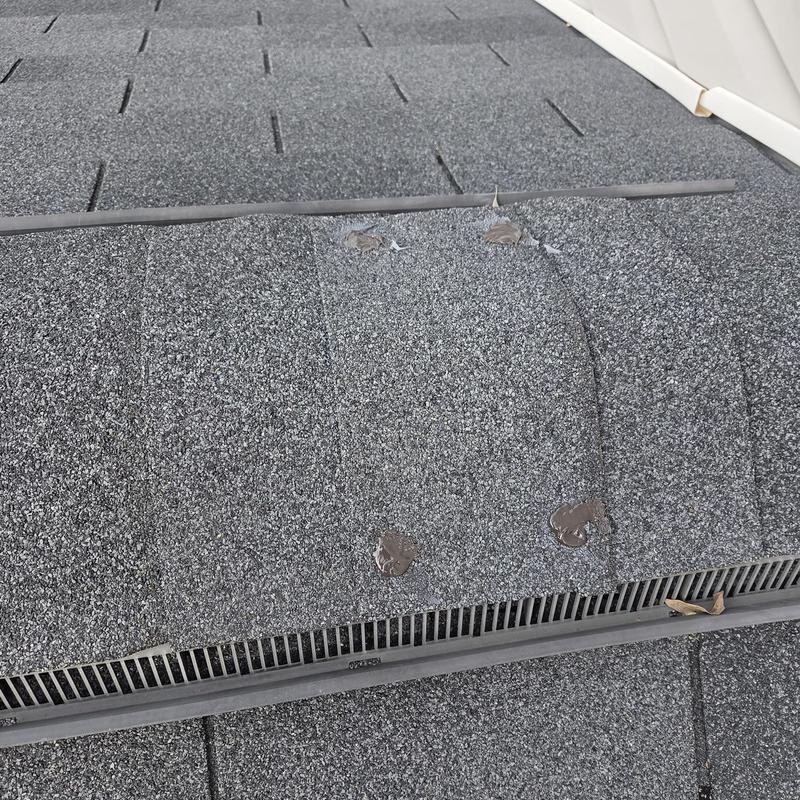 Asphalt shingles with caulked nail heads on roof ridge
