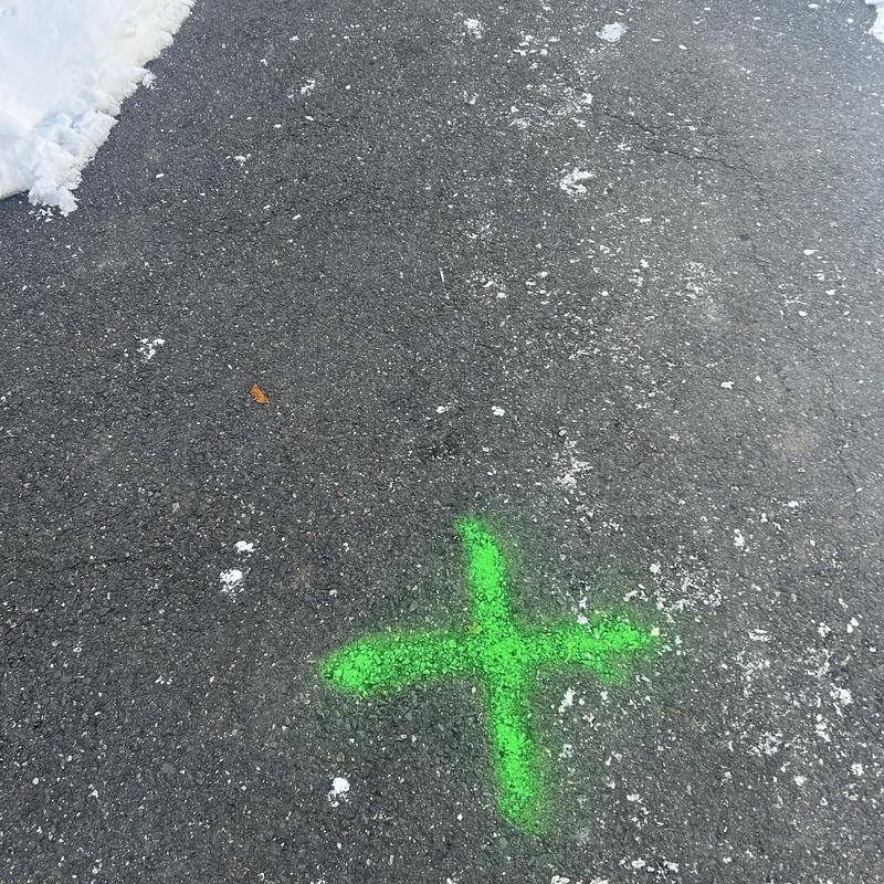 Main line sewer location marked on asphalt driveway